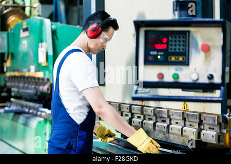Asian machine operator in production plant checking data Stock Photo