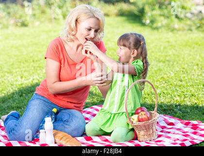 Happy family at summer vacation concept. Mother and daughter little girl having picnic playing in park outdoors. Stock Photo