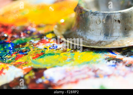 A macro of 3 dabs of Artist's acrylic paints in the primary colors red,  yellow and blue with additional tubs of paint and an artist's paint brush  in t Stock Photo - Alamy