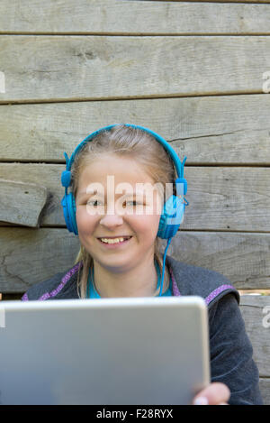 Girl listening music on digital tablet in playground, Munich, Bavaria, Germany Stock Photo