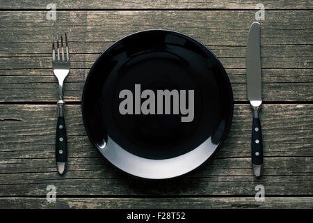 empty plate with fork and knife on the vintage wooden table Stock Photo