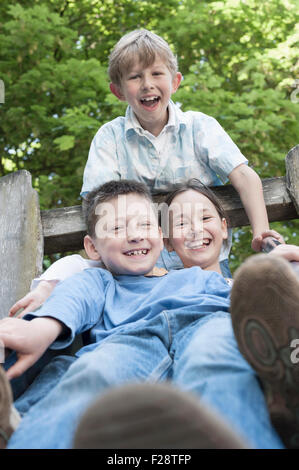 Three friends having fun on slide in playground, Munich, Bavaria, Germany Stock Photo