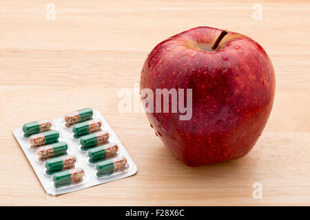 Green capsules bliter pack and fresh red apple Stock Photo