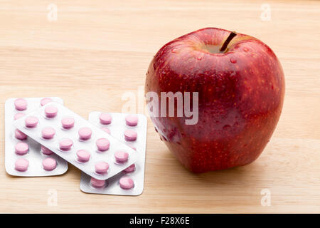 Pink pills blister pack and fresh red apple Stock Photo