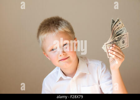 Happy smiling child with money (dollars) in hand on gray background
