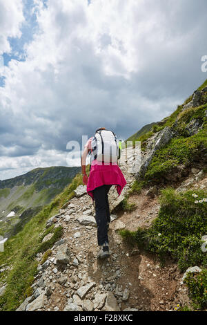 Woman hiker on a mountain trail in a spectacular scenery Stock Photo