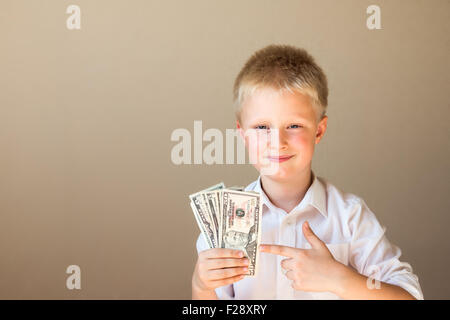 Happy smiling child with money (dollars) in hands on gray background