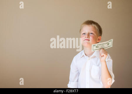 Happy smiling child with money (20 dollars) in hand on grey background Stock Photo