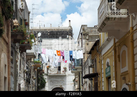 Clothes hanging out to dry on a clothesline across a street in Matera. Stock Photo