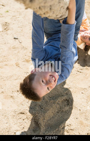 Boy and girl hanging upside down from rope in playground, Munich, Bavaria, Germany Stock Photo