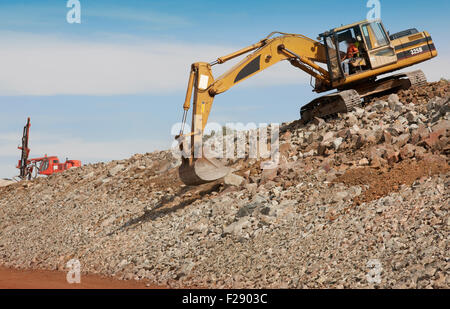 Excavator unloading sand at eathmoving works in construction site and drilling machine. Stock Photo