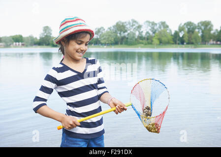 Girl holding stones in fishing net, Bavaria, Germany Stock Photo