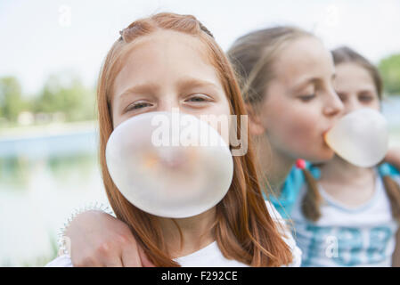 Girls blowing chewing gum bubbles, Bavaria, Germany Stock Photo