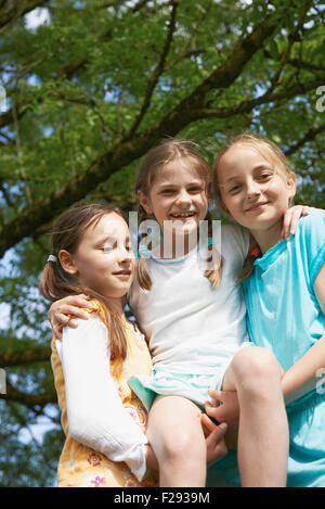 Two girls lifting their female friend and smiling, Bavaria, Germany Stock Photo