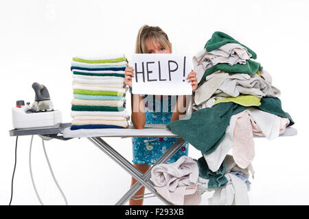 Woman behind a board covered with clothes to be ironed, exposes a sign reading aid Stock Photo