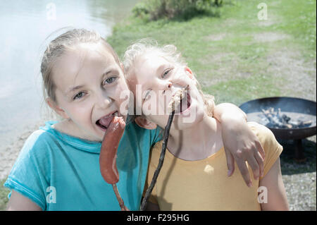 Two friends eating sausage and bread at lakeshore, Bavaria, Germany Stock Photo