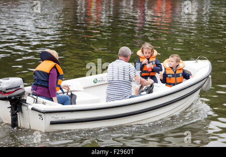Family in a hired motorboat all wearing life jackets except the male, on the River Avon, Warwickshire, England, UK Stock Photo