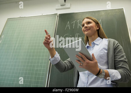 School teacher in front of blackboard in classroom, Munich, Bavaria, Germany Stock Photo