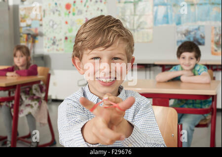 schoolboy with a slingshot and smiling in classroom, Munich, Bavaria, Germany Stock Photo
