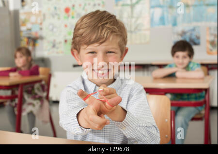 schoolboy with a slingshot and smiling in classroom, Munich, Bavaria, Germany Stock Photo