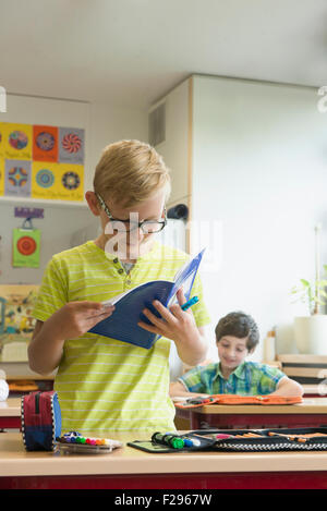 schoolboy reading a book in classroom, Munich, Bavaria, Germany Stock Photo