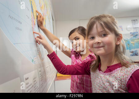 schoolgirls studying a map of the world in classroom, Munich, Bavaria, Germany Stock Photo