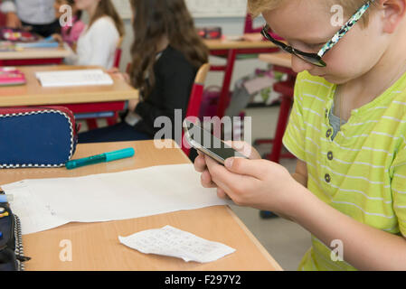 Close-up of a schoolboy using smart phone in classroom, Munich, Bavaria, Germany Stock Photo