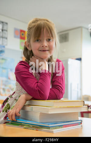 Portrait of a schoolgirl leaning on books, Munich, Bavaria, Germany Stock Photo