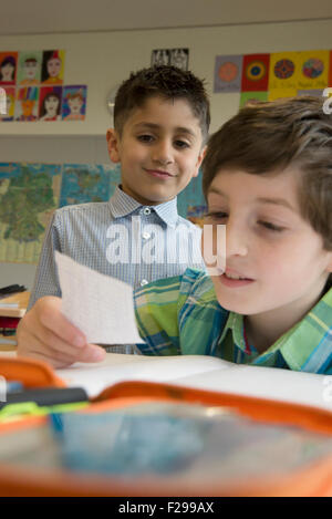 schoolboys reading a message in classroom, Munich, Bavaria, Germany Stock Photo