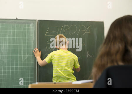 schoolboy writing on blackboard in classroom, Munich, Bavaria, Germany Stock Photo
