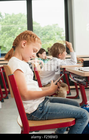 Side profile of a schoolgirl using a smart phone in classroom, Munich, Bavaria, Germany Stock Photo