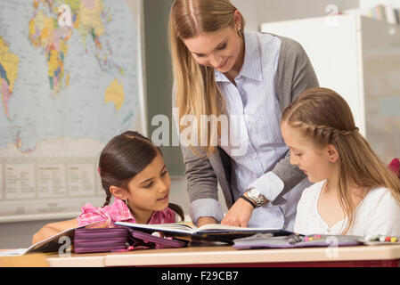Female teacher helping students in classroom, Munich, Bavaria, Germany Stock Photo