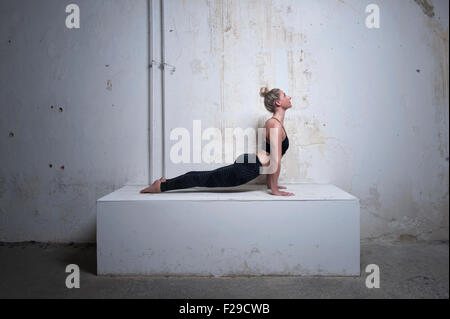 Mid adult woman practicing upward facing dog position on concrete block, Munich, Bavaria, Germany Stock Photo