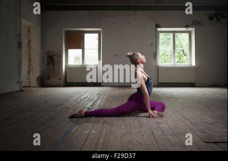 Mid adult woman practicing pigeon pose in yoga studio, Munich, Bavaria, Germany Stock Photo