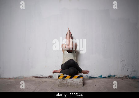 Mid adult woman practicing cow face pose in yoga studio, Munich, Bavaria, Germany Stock Photo