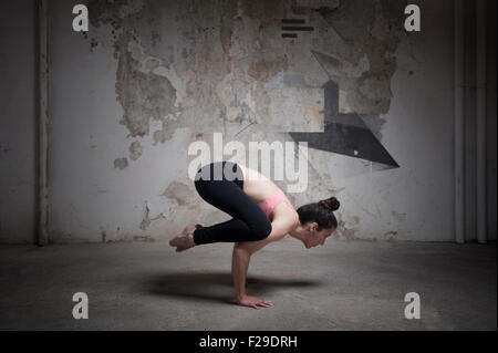 Mid adult woman practicing bakasana in yoga studio, Munich, Bavaria, Germany Stock Photo