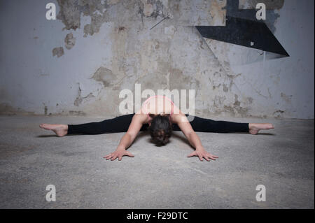 Mid adult woman practicing wide angle seated forward bend pose in yoga studio, Munich, Bavaria, Germany Stock Photo