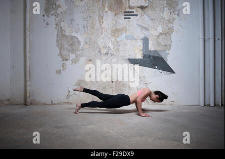 Mid adult woman practicing plank pose in yoga studio, Munich, Bavaria, Germany Stock Photo