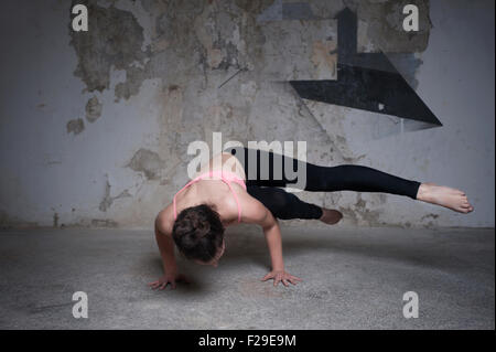 Mid adult woman practicing parsva bakasana pose in yoga studio, Munich, Bavaria, Germany Stock Photo