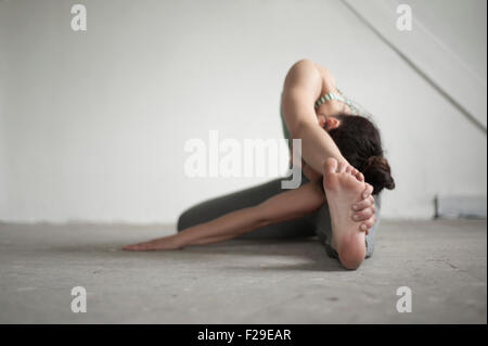 Mid adult woman practicing janu sirsasana pose in yoga studio, Munich, Bavaria, Germany