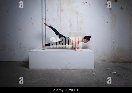 Mid adult woman practicing plank pose on concrete block, Munich, Bavaria, Germany Stock Photo