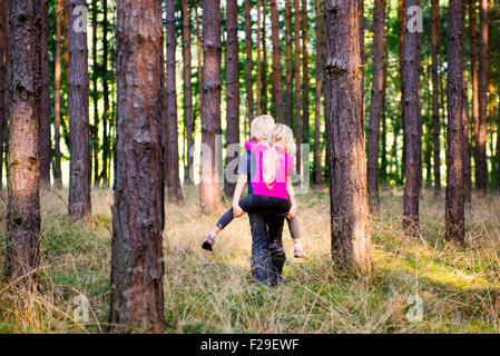 Young boy giving young girl piggyback outdoors smiling, forest, woodland, wood, summer, holiday, siblings, children playing, kid Stock Photo