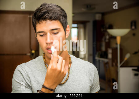 Close up Handsome Young Man Applying Lip Balm with a Serious Facial Expression. Stock Photo