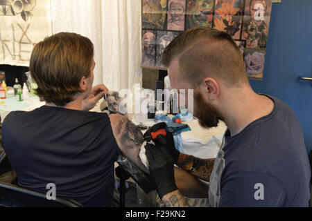 Garden City, New York, USA. 13th Sep, 2015. R-L, GUNNAR VALDIMARSSON, from Akureyri, Iceland, is tattooing the arm of his brother KRISTJAN VALDIMARSSON, at the United Ink Flight 915 Tattoo convention at the Cradle of Aviation Museum in Long Island. The brothers are from Iceland, and the tattoo has a Nordic Viking theme. © Ann Parry/ZUMA Wire/Alamy Live News Stock Photo
