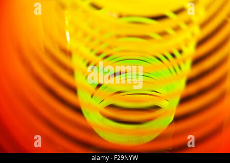 Rainbow coloured slinky toy made of a plastic wire spiral coil which enables flexibility and mobility Stock Photo