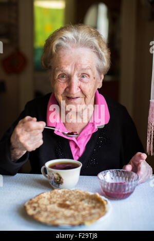 An elderly woman drinking tea in the kitchen. Stock Photo