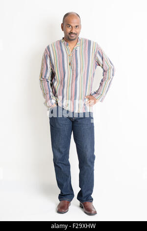 Full length confident mature casual Indian man standing on plain background with shadow. Stock Photo