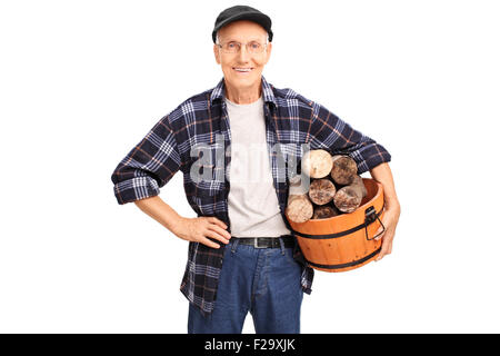 Cheerful senior in a blue checkered shirt holding a basket full of logs and smiling isolated on white background Stock Photo