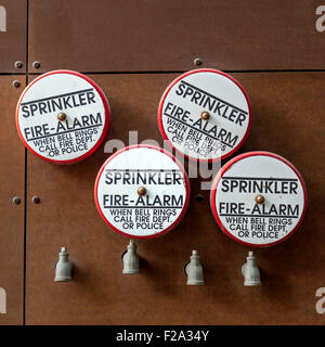 Fire alarm bell equipment with water sprinklers hanging on building wall Stock Photo