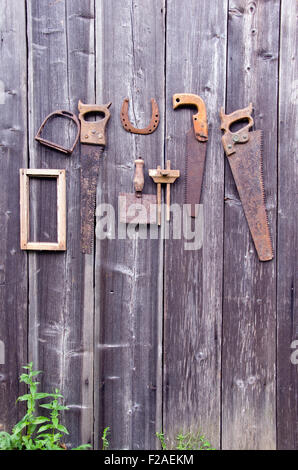 Antique handicraft tools and horseshoe hanging on old wooden barn wall Stock Photo